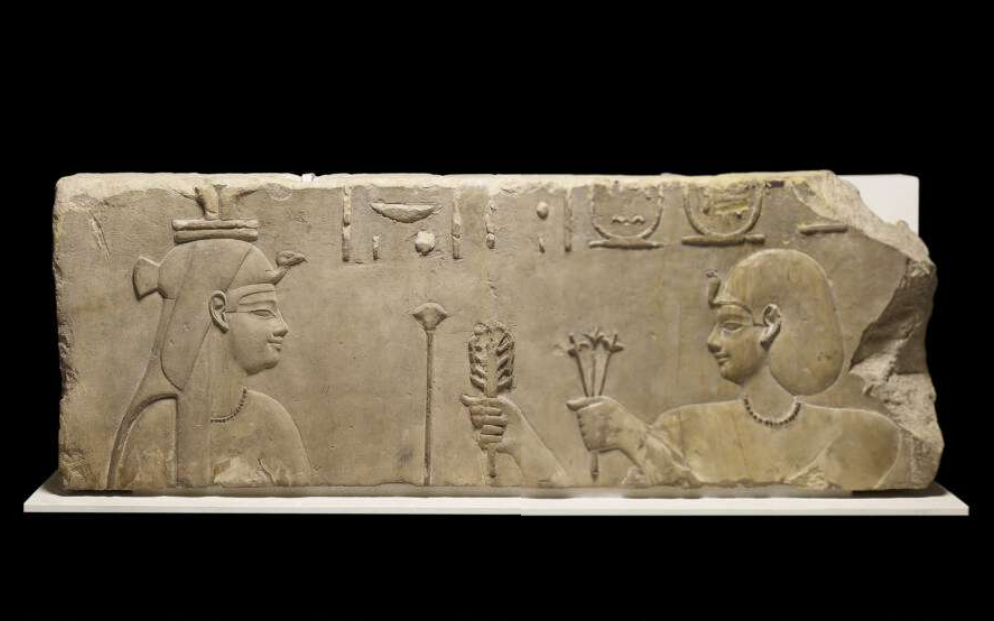 Limestone temple-relief of Ptolemy I Soter making an offering to Hathor. Ptolemy stands to the right, facing Hathor on the left, and wards a necklace of beads as he presents plants of Upper and Lower Egypt and papyrus to Hathor.